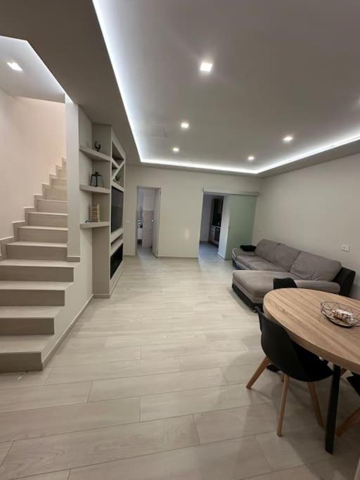 sala de estar con sofá, mesa y escaleras en Casa Accogliente con terrazza, en Ariano Irpino