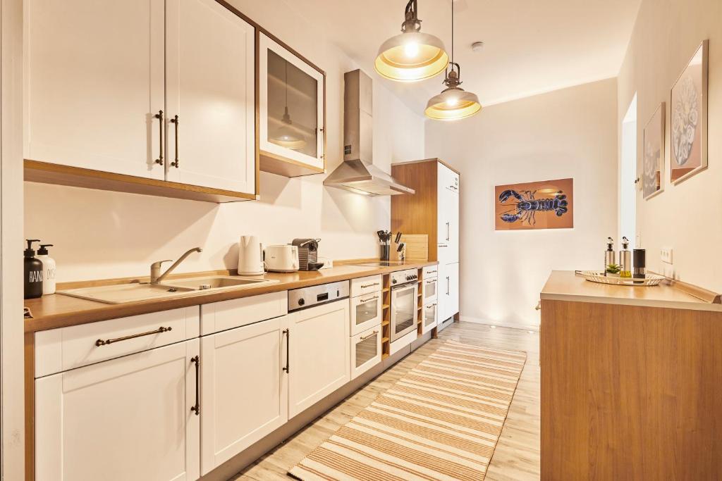 Eine Küche mit weißen Schränken und Holzboden in der Unterkunft OLIVE Apartments - Terrasse - Zentral in Hannover