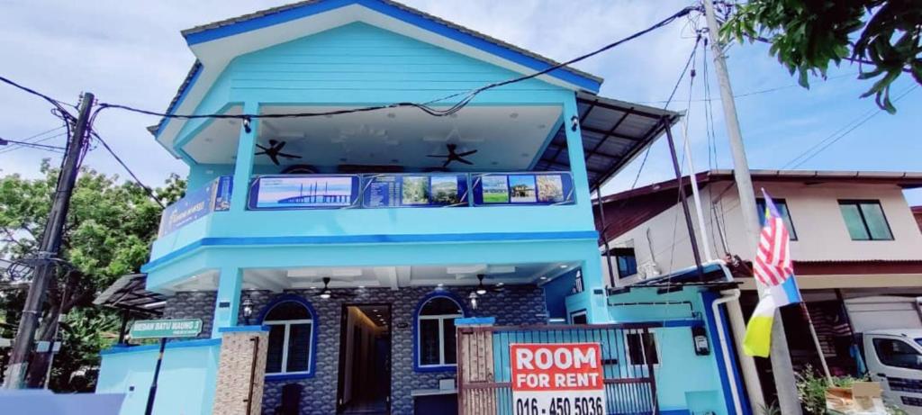 Kampong Batu MaungSunStar Hotel的蓝色房子,前面有出租的标志