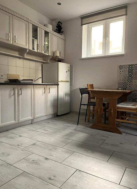 a kitchen with white cabinets and a table with chairs at Apartament 01 in Poznań