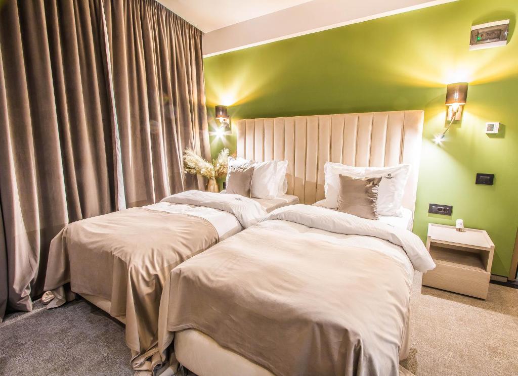 two beds in a bedroom with a green wall at Central Apart Hotel in Bucharest