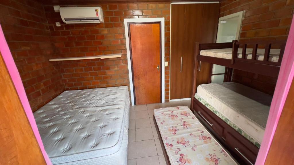 a small room with two bunk beds and a door at Chalé Lazer Gravatá com 3 suítes - na Suíça Brasileira in Gravatá