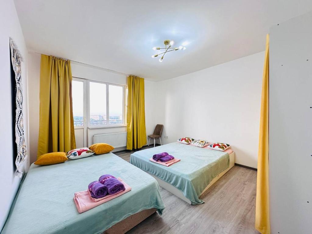 two beds in a room with yellow curtains at Гавань Счастья in Almaty