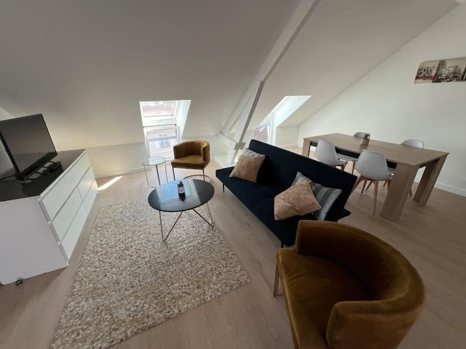 ein Wohnzimmer mit einem blauen Sofa und einem Tisch in der Unterkunft Appartement neuf proche gare in Margny-lès-Compiègne