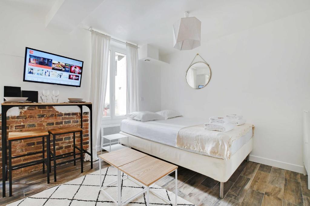 une chambre blanche avec un lit et une télévision dans l'établissement Charming studio - 2P - Center of Paris, à Paris