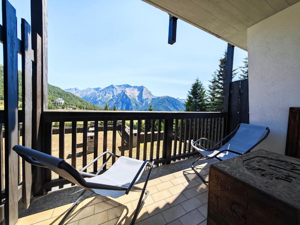 two chairs and a table on a balcony with mountains at Hostdomus - Pastore Apartment in Sestriere