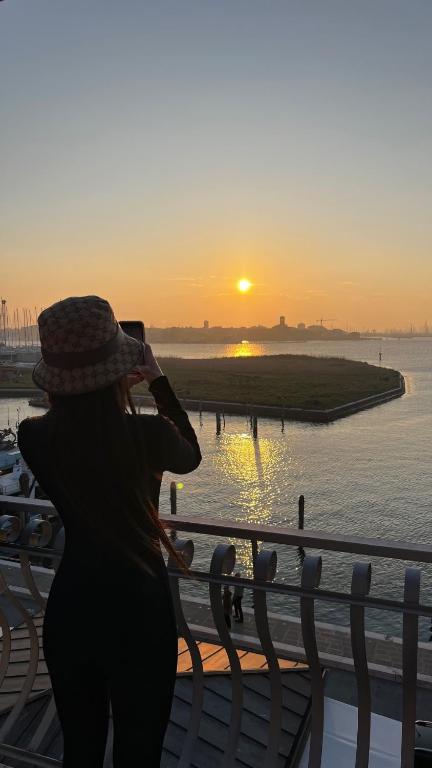 a woman taking a picture of the sunset at Appartamenti Bellavista 107 in Chioggia