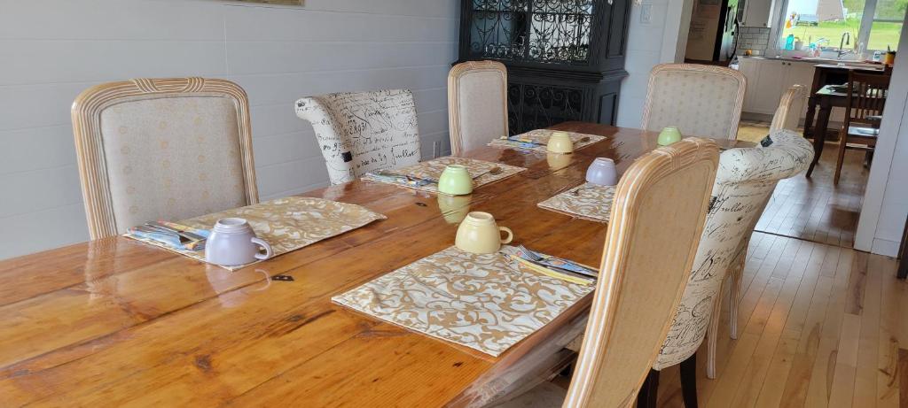a dining room table with chairs and a wooden table with at Auberge Évasion Nature Petite-Vallée in Petite-Vallée