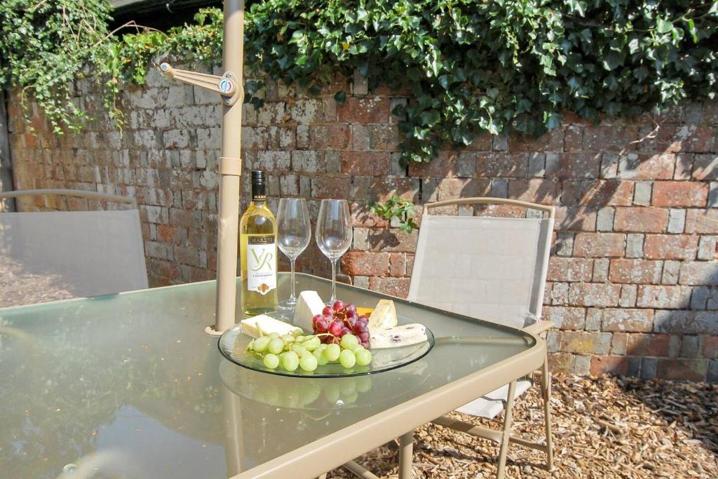 a glass table with a plate of fruit and wine glasses at Peaceful first floor apartment close to town centre in Horsham