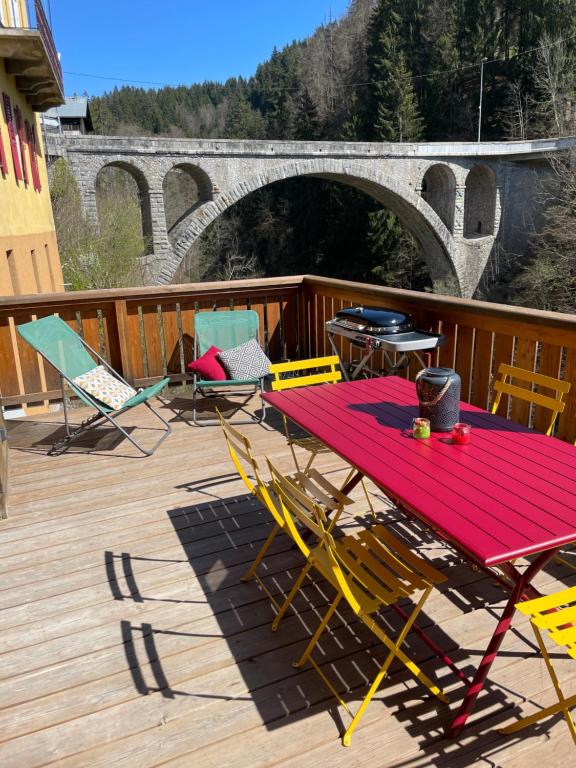 a red table and chairs on a deck with a bridge at Espace Diamant - Duplex typiquement Savoyard in Flumet