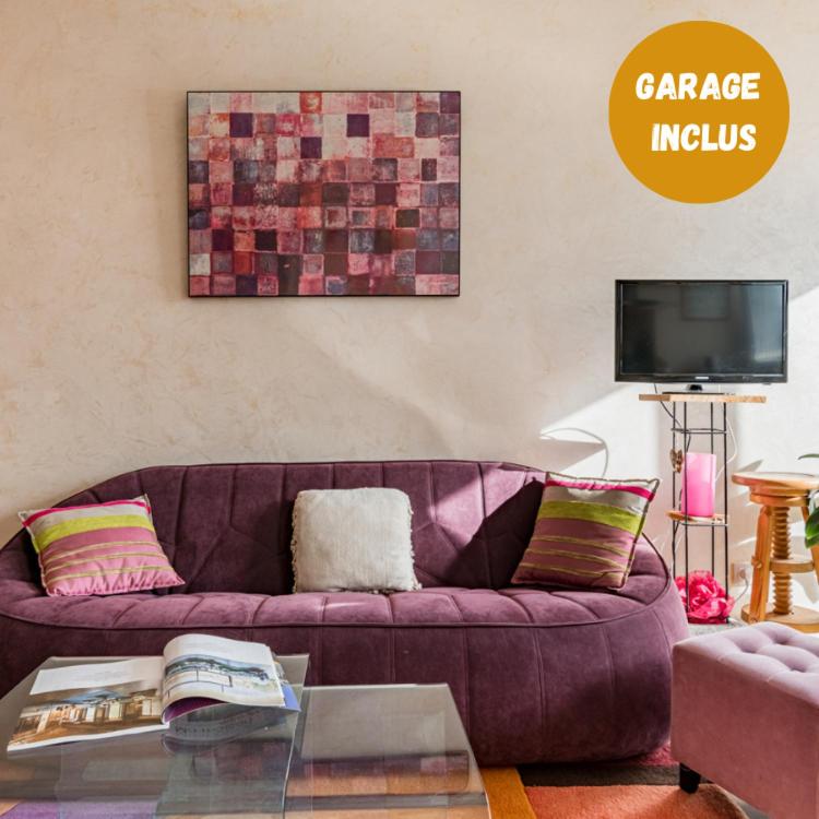 - un canapé violet dans le salon avec une télévision dans l'établissement Le Célestine Très joli T2 centre ville -Garage, à Saint-Étienne