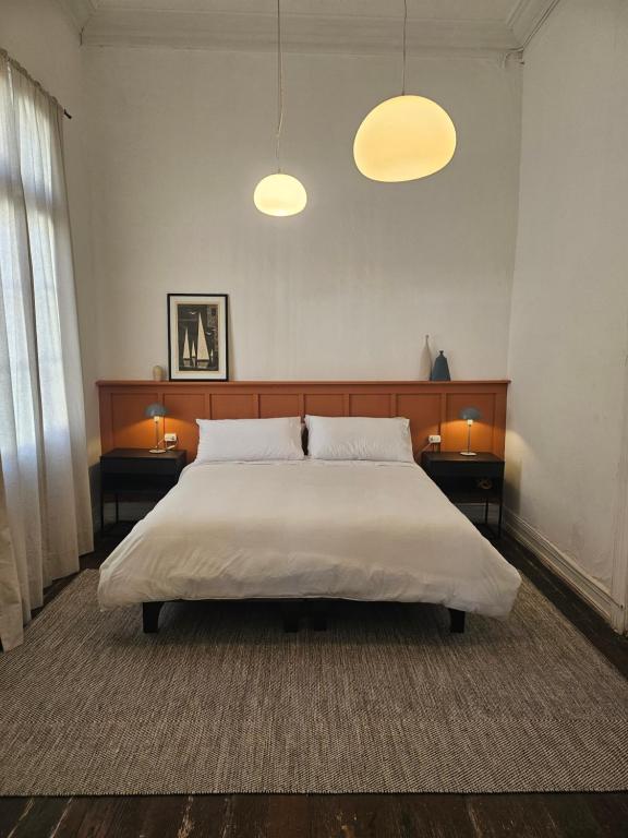 a bedroom with a large bed with two tables and two lights at La Puerta Roja in Valparaíso
