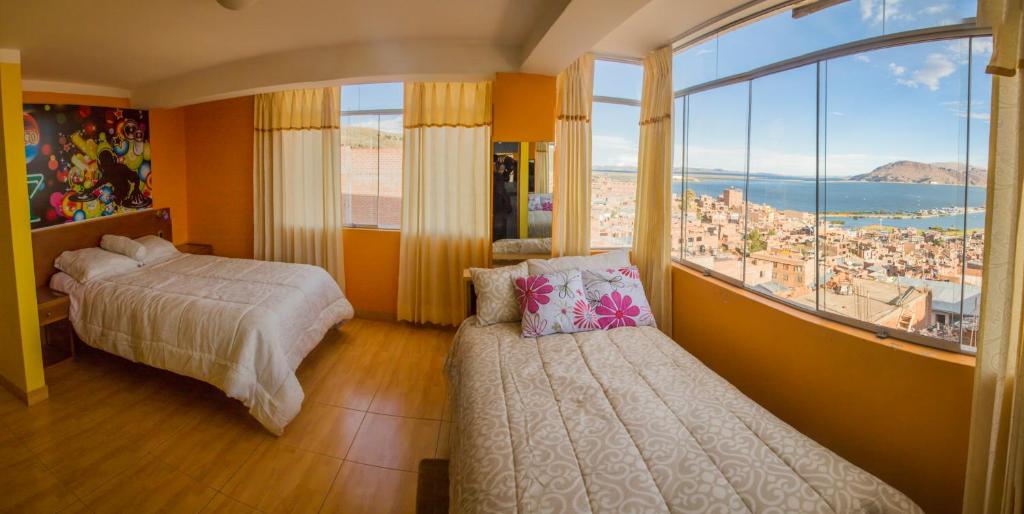 een slaapkamer met 2 bedden en een groot raam bij Wisny Inn in Puno