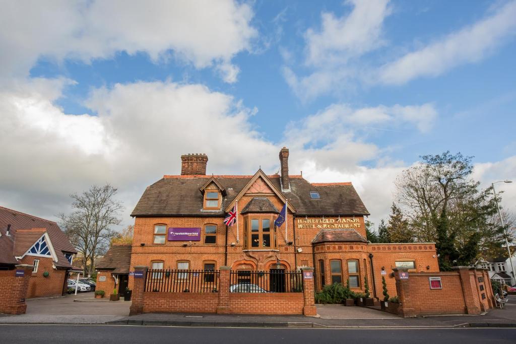 una vieja casa de ladrillo con una bandera. en Harefield Manor Hotel en Romford