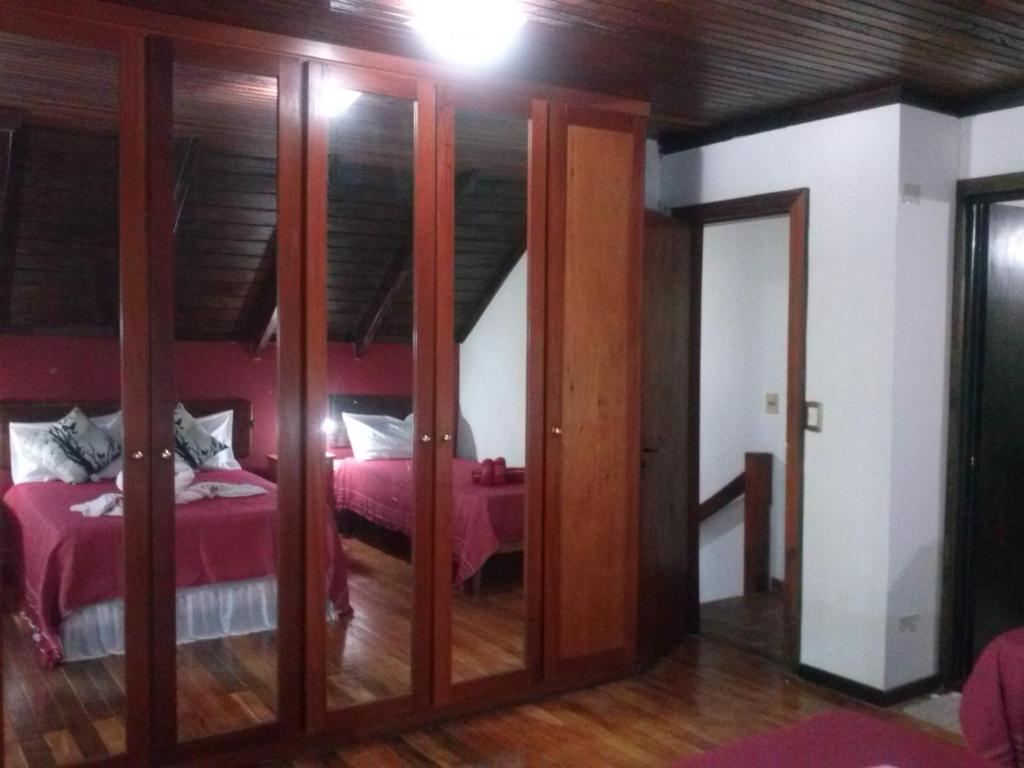 - une chambre avec un lit rose et des portes en verre dans l'établissement Petit Hotel Caraguata, à Puerto Iguazú