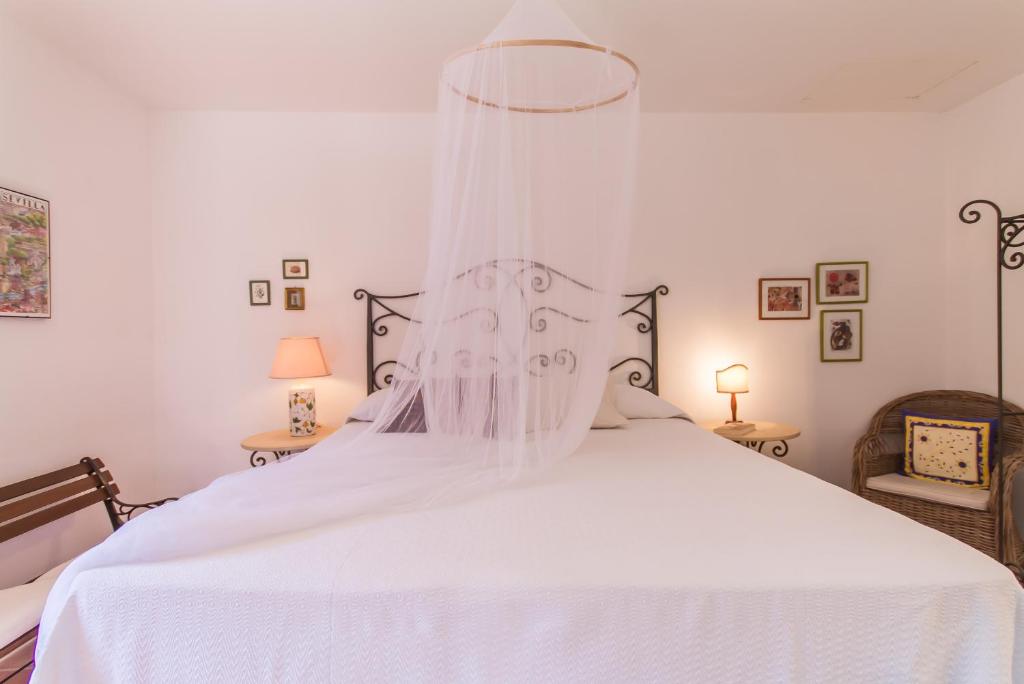 a bedroom with a white bed with a canopy at Santolìo Country Retreat - Relax in Masseria Siciliana con Giardino e Vista in Palazzolo Acreide