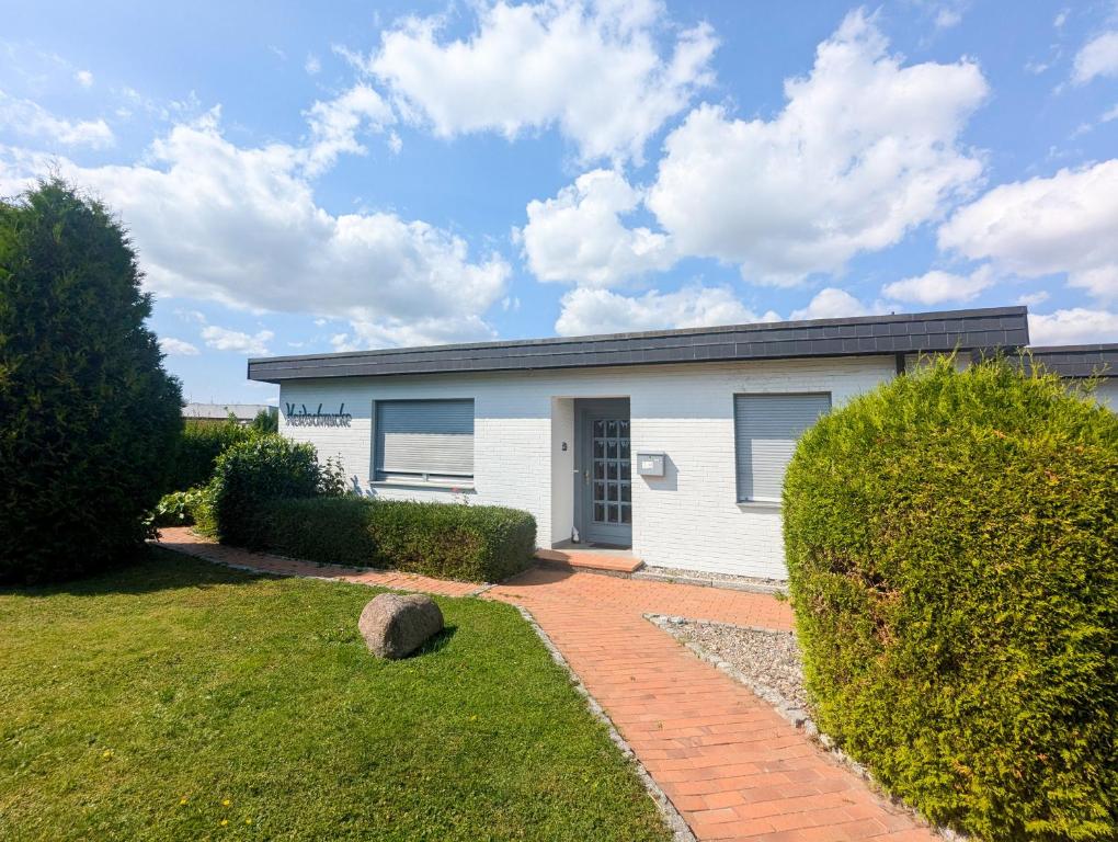 ein weißes Haus mit einer steinernen Einfahrt in der Unterkunft Bungalow Vaupel in Kellenhusen