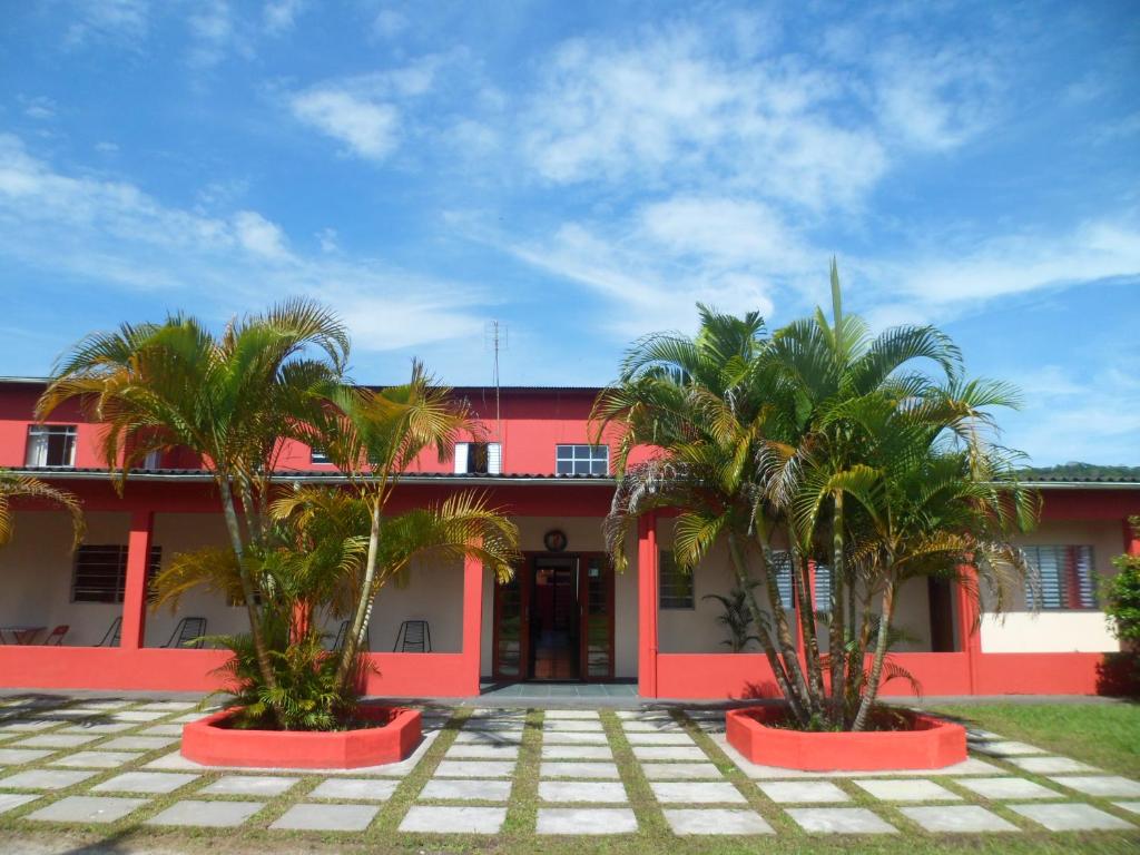 dos palmeras frente a un edificio rojo en Candairó Hotel Pousada, en Cananéia
