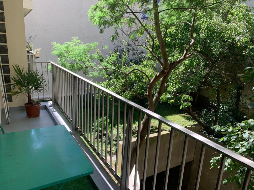 d'un balcon avec une table verte et un arbre. dans l'établissement Cosy family flat, à Clichy