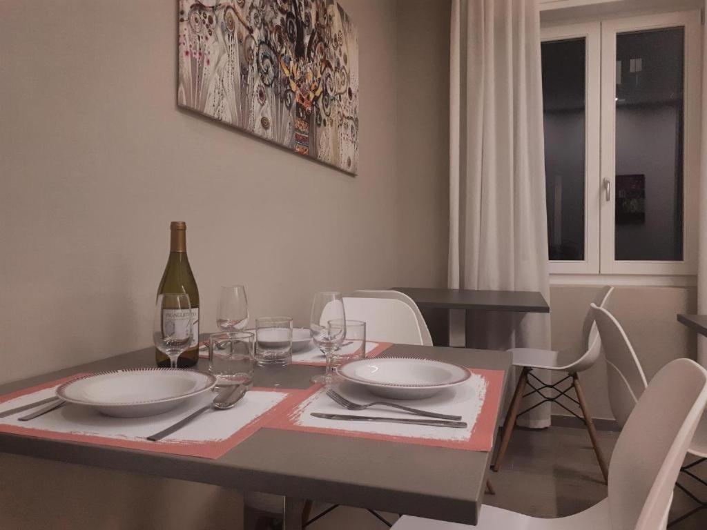 einen Esstisch mit weißen Stühlen und eine Flasche Wein in der Unterkunft Smart Apartment Sei Chiese - TWA in Bologna