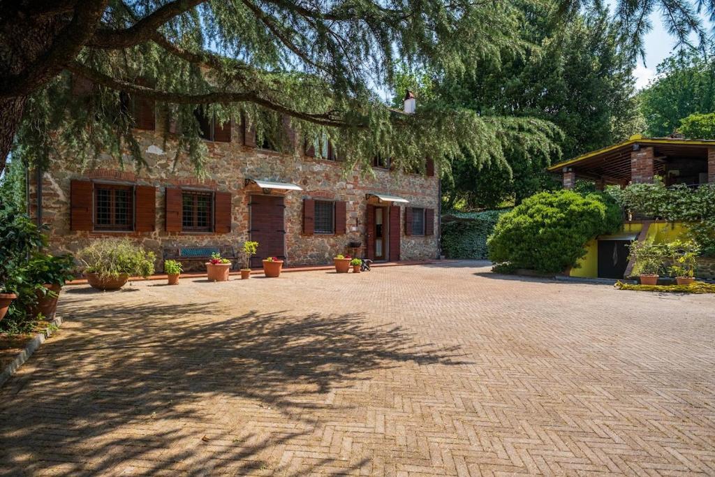 een huis met een grote boom die over een bakstenen oprit hangt bij Casolare Oltre il Cielo in Porcari