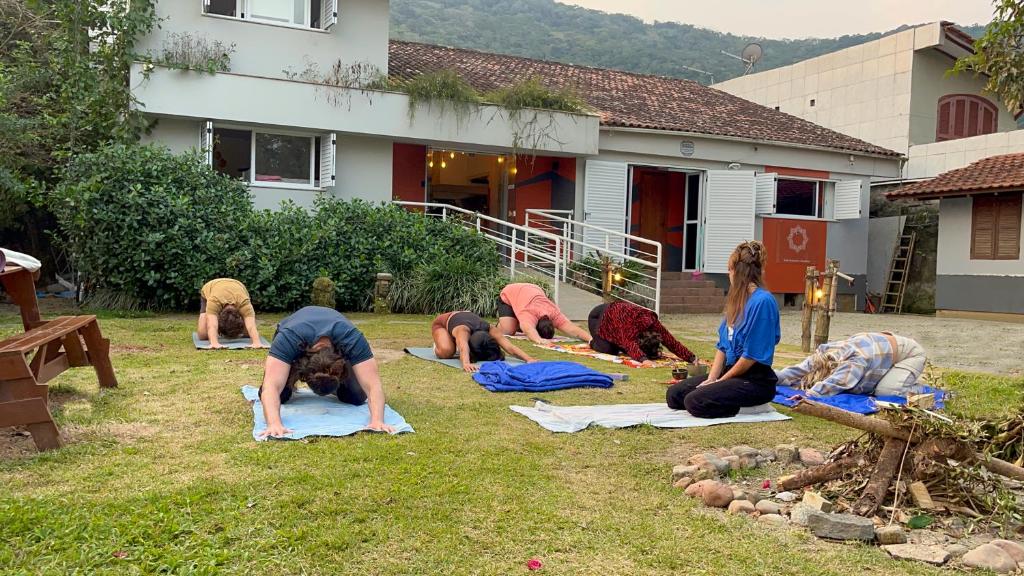 een groep mensen die yoga doen in het gras bij Nômades Vibe da Ilha - Adventure Hostels in Florianópolis