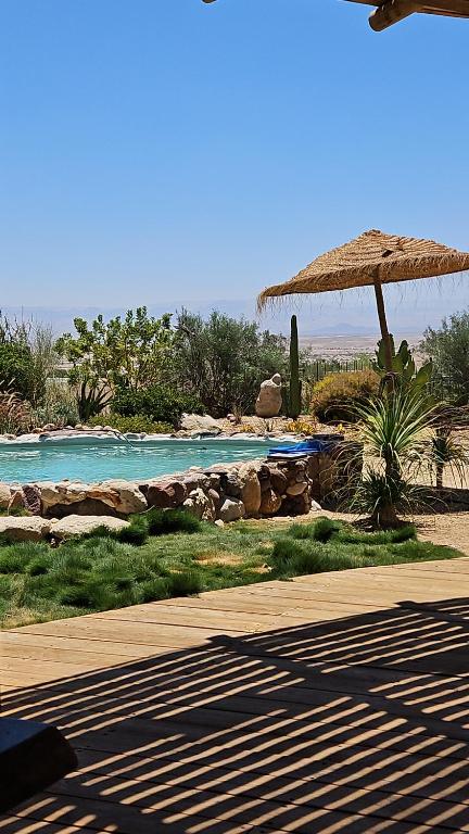 un complejo con piscina y sombrilla de paja en בית האבן בצוקים, en Tzukim