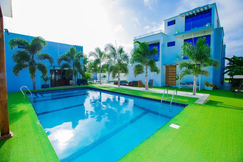 a swimming pool in front of a blue building at Kibada White Villa in Dar es Salaam