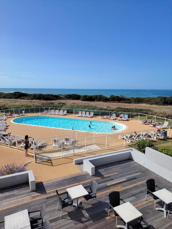 - une piscine avec des tables et des chaises et l'océan dans l'établissement Appartement forever, à Les Sables-dʼOlonne