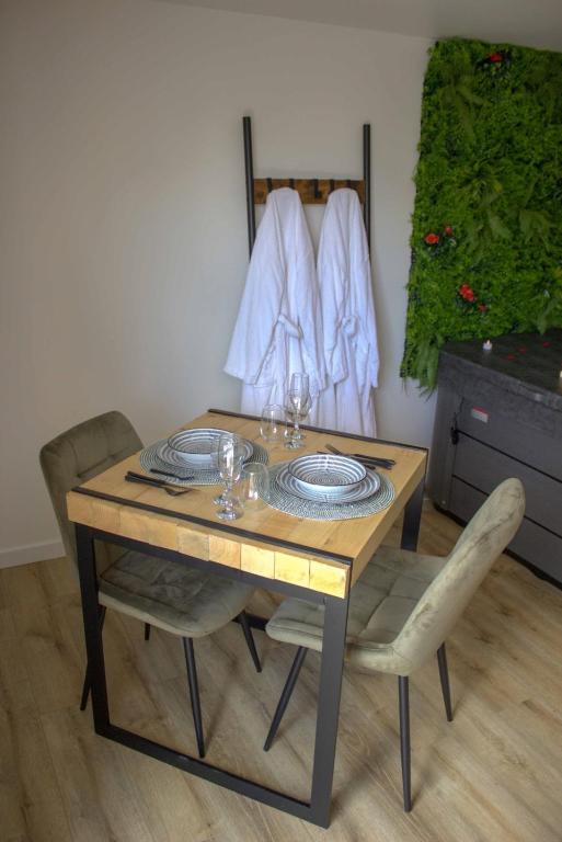 - une table en bois avec des chaises et des assiettes dans l'établissement La romance champêtre, à La Noë-Blanche