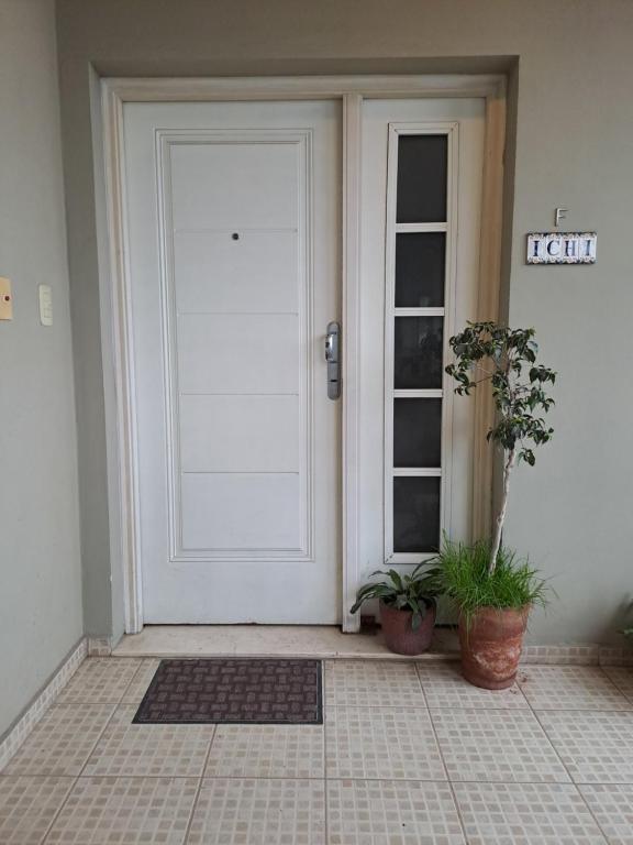 a white door with two potted plants in front of it at Hermoso y luminoso departamento in Yerba Buena
