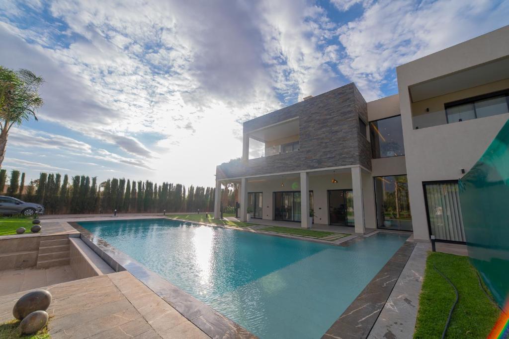 a house with a swimming pool in front of it at Villa vue atlas marrakech in Marrakech