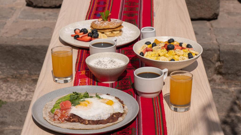 a table with plates of breakfast foods and drinks at Viajero Cusco Hostel in Cusco