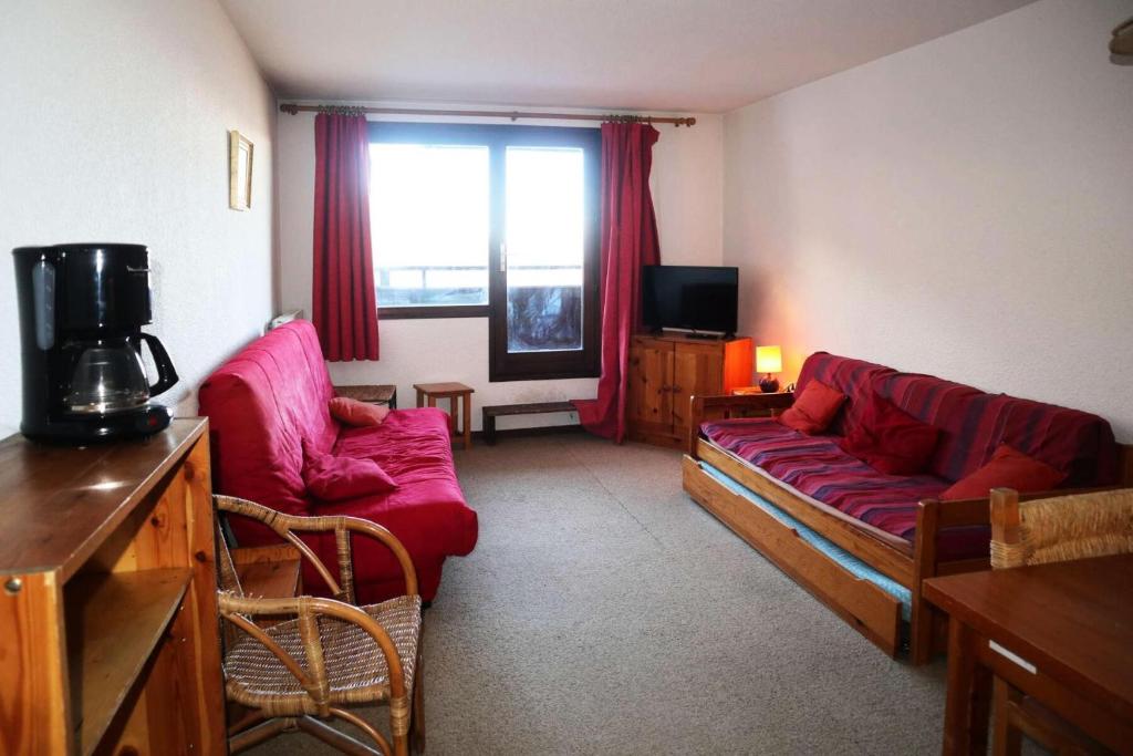 un salon avec un canapé rouge et une télévision dans l'établissement Résidence Le Cairn - STUDIO N° 0507 LE CAIRN MAE-4531, aux Orres