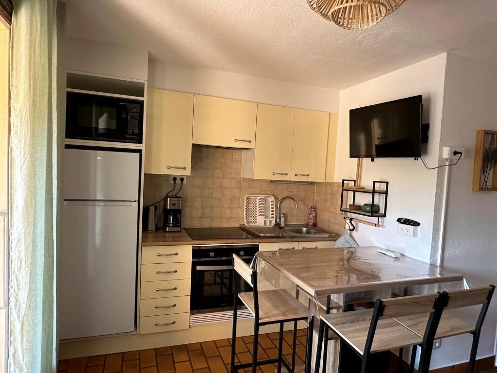 une cuisine avec un réfrigérateur blanc et une table dans l'établissement Studio l Arbanais, à Hyères