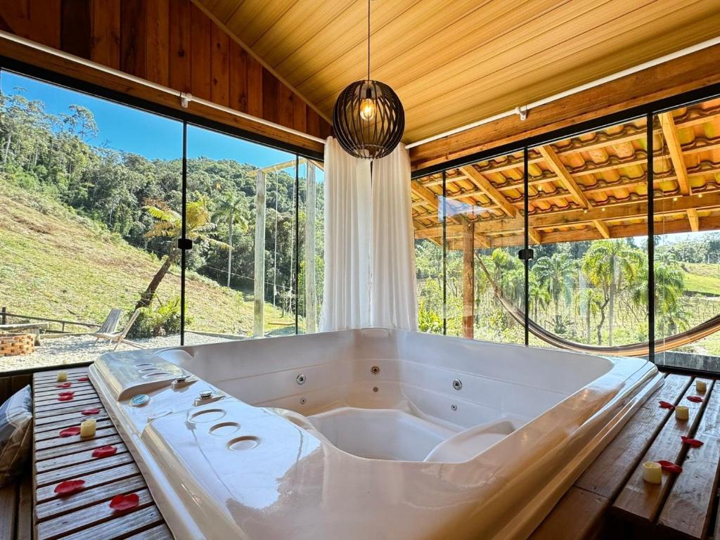 a large bath tub in a room with large windows at Sítio Raizes da Videira - SRR004 in Pinheiral