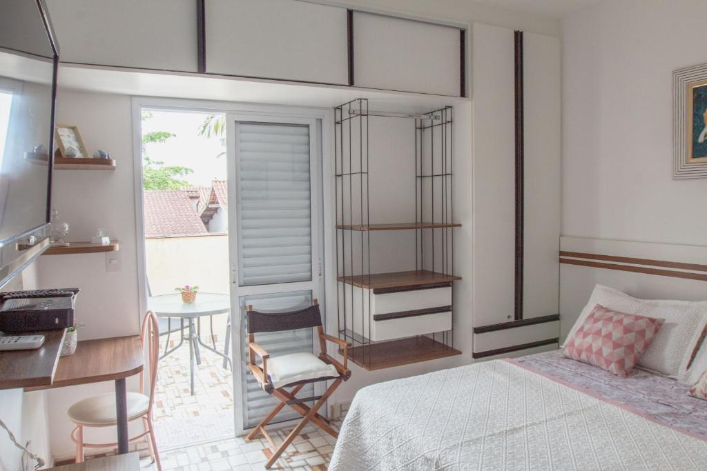 ein Schlafzimmer mit einem Bett, einem Schreibtisch und einem Tisch in der Unterkunft Suite Casal Mar e Lua em casa compartilhada in Ubatuba