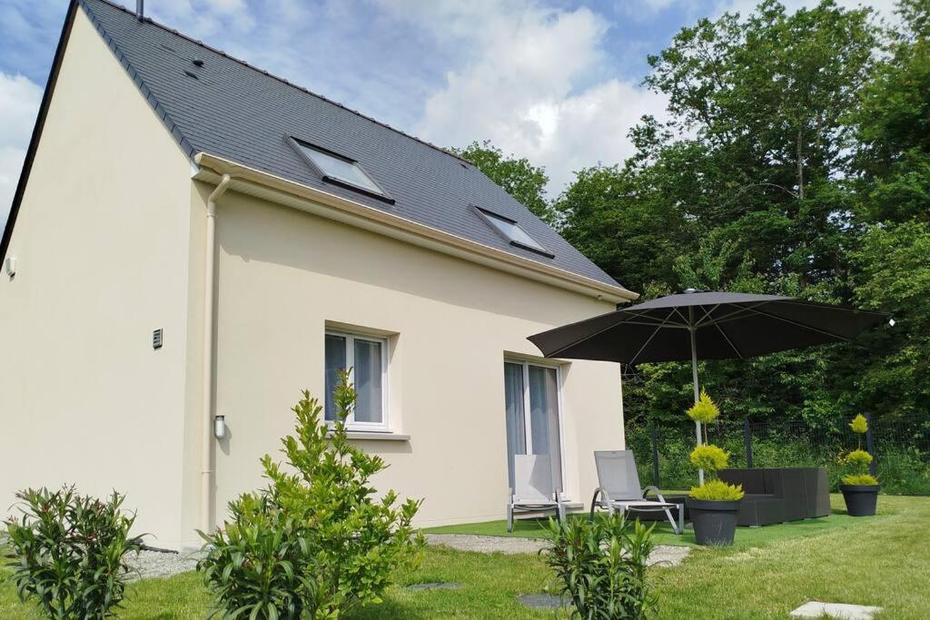 une maison blanche avec un parasol et une chaise dans l'établissement Le Royaume des Sens, à Sainte-Opportune-du-Bosc