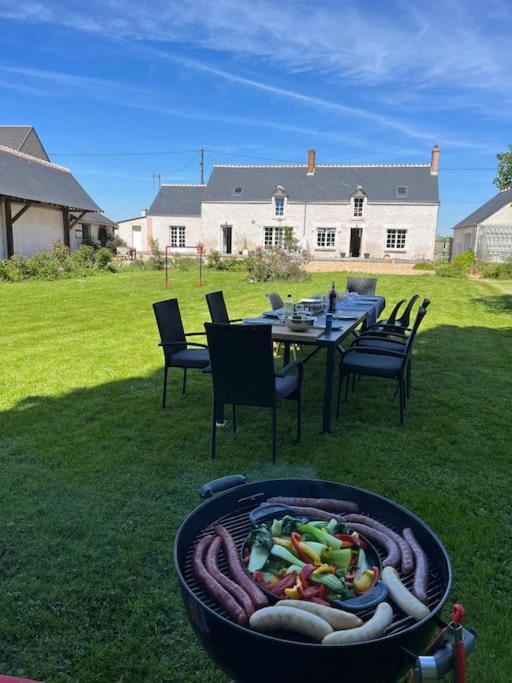 une table et des chaises dans une cour avec un foyer dans l'établissement Maison au calme, à Baccon