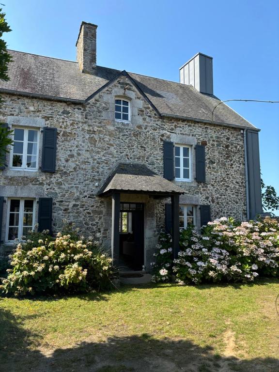une vieille maison en pierre avec des fleurs devant dans l'établissement Maison de charme proche mer, à Blainville-sur-Mer