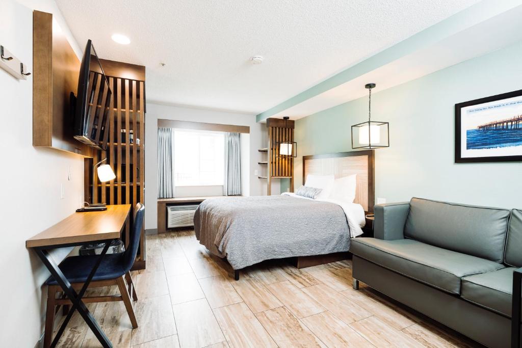 a bedroom with a bed and a desk and a couch at The Windstar Hotel - Carolina Beach in Carolina Beach