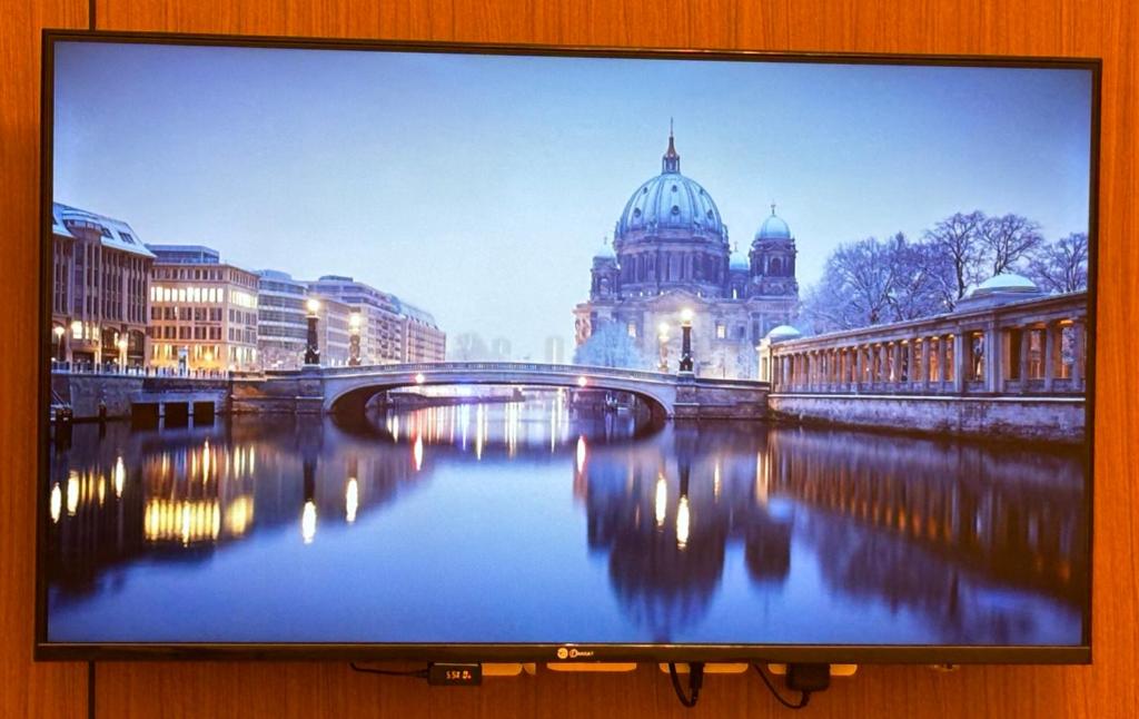 a television screen with a picture of a bridge and a building at شقه مفروشه مميزه 3 in Obhor