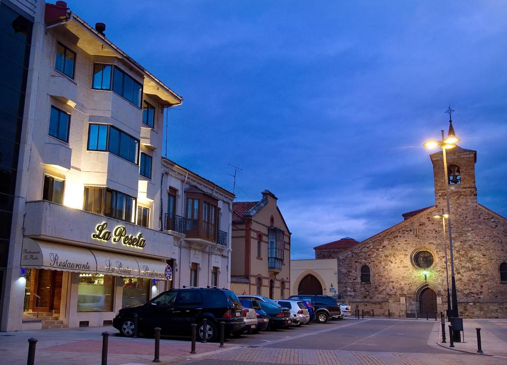 een straat met auto's geparkeerd voor een gebouw bij Hotel Restaurante La Peseta in Astorga