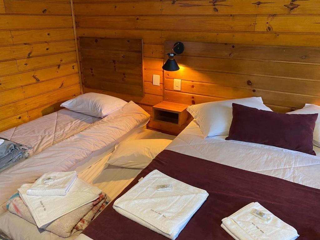 two beds in a room with wooden walls at Cabanas Colina Do Sol in Cambara do Sul