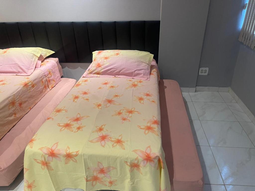ein Bett mit einer gelben Decke mit rosa Blumen drauf in der Unterkunft Loft 601 in Rio de Janeiro