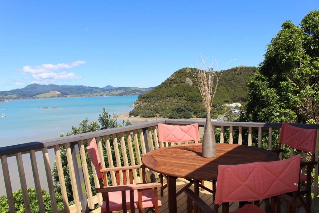 ein Tisch und Stühle auf einem Balkon mit Blick auf das Meer in der Unterkunft Skyehaven Holiday Home - Coromandel Town in Coromandel Town