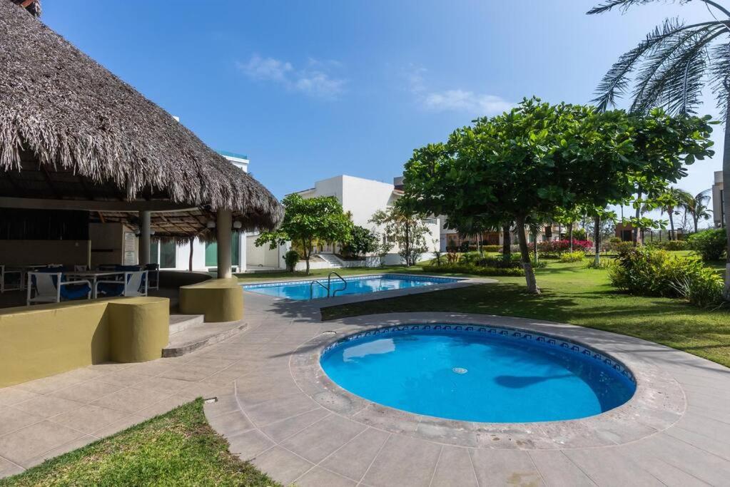 a swimming pool in a resort with a thatch roof at Casa Flamingos Coco in Mezcales