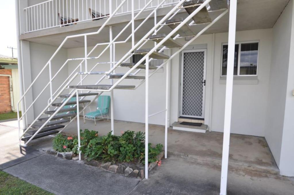 a white staircase next to a house with a chair at The Sea Ranch 2 Unit 2, 45 Beech Street Evans Head in Evans Head