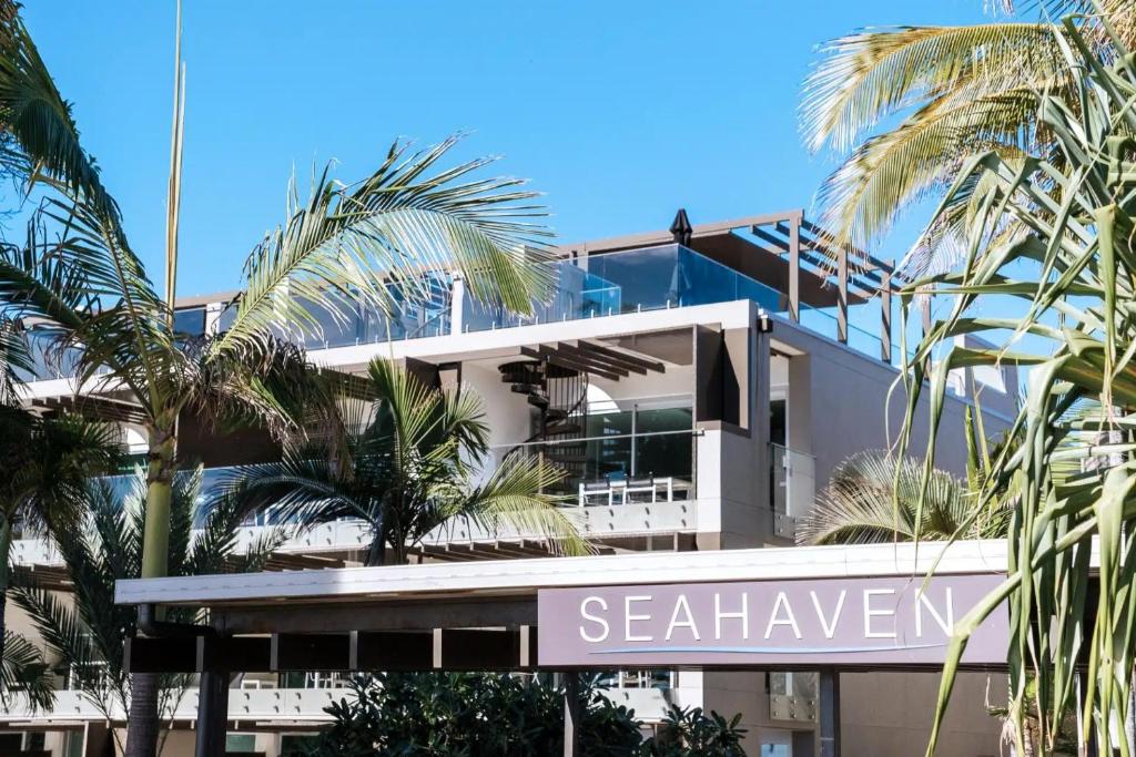 un edificio bianco con palme di fronte di Seahaven Noosa Beachfront Resort a Noosa Heads