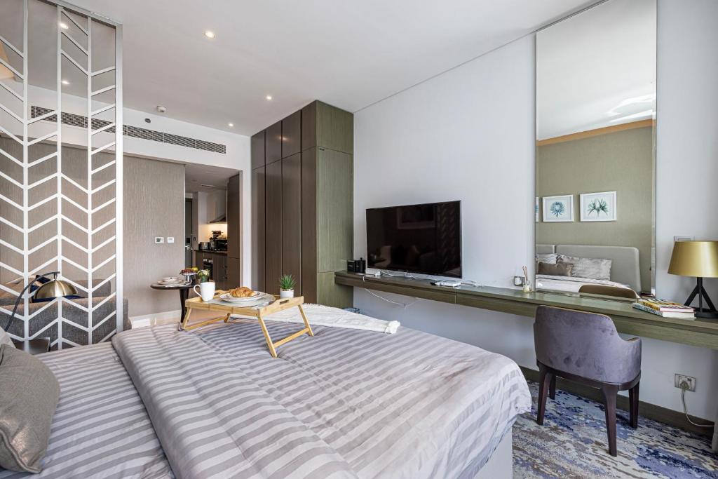 a bedroom with a bed and a desk and a tv at Livin' Holidays - Luxury studio with Bay view in Dubai